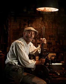 Man with hat and cigarette repairing a motor in a workshop