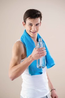 Smiling young man after doing sport holding a water bottle in his hand