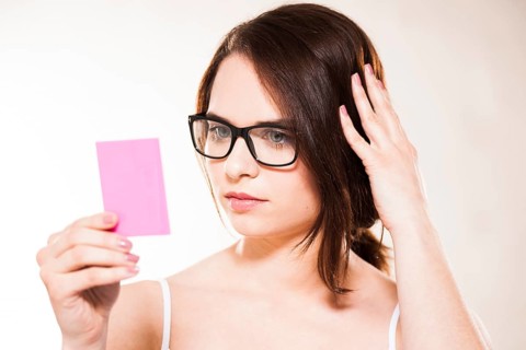 Young woman looking at herself in a cosmetic mirror
