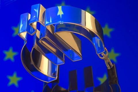 Miniature figure of a worker is carrying the Euro-symbol