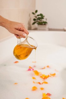 Woman pouring bath oil in a bathtub