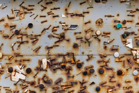 Remnants of rusted tacks and staples on a board