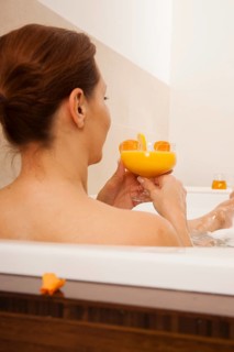 Woman taking a bath and drinking a juice