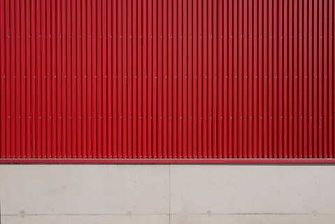 Wall of a factory building with red corrugated iron and concrete