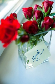 Red roses in vase with a note 'Merci'