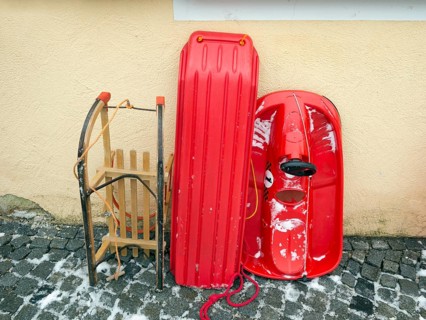 Various sledges leaning against a house wall