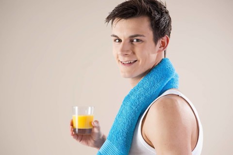 Smiling young man after doing sport holding a glass of juice in his hand