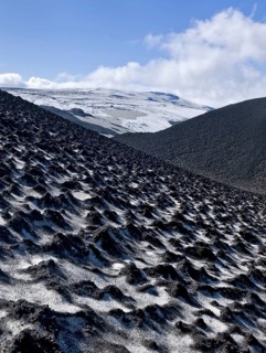 Ash-covered snowfield with the Eyjafjallajokull on the long-distance hiking trail from Skogar via Fimmvorouhals to the Thorsmork mountain ridge