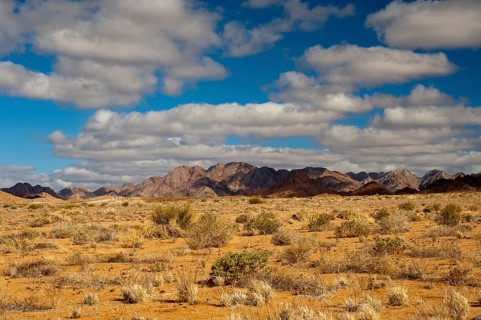 A blue sky with white clouds over the mountainous desert landscape