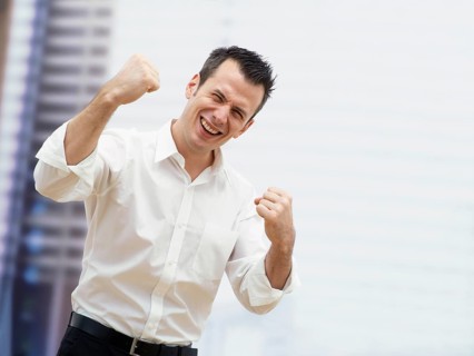 Businessman in an office cheering with clenched fists