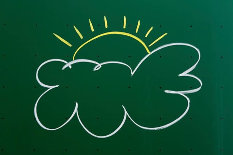Cloud with a sun drawn with chalk on a blackboard
