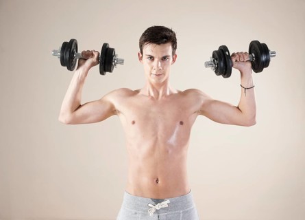 Young man doing weight training with dumbbells
