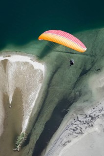 Paraglider over the Maggia river delta with naturally formed water and rocks terrain