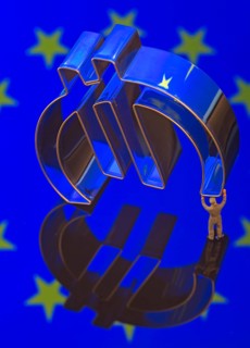 Miniature figure of a worker is carrying the Euro-symbol
