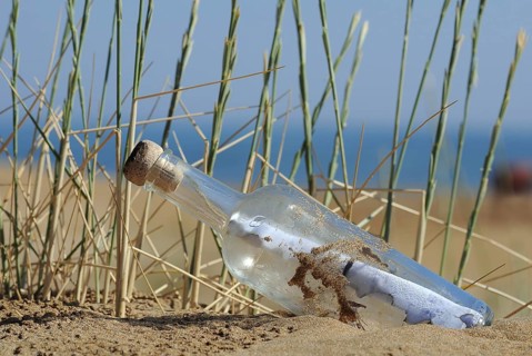 Message in a bottle in sand on a beach