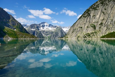 Mountains around the Grimsel Pass are reflected in Gelmerstausee reservoir