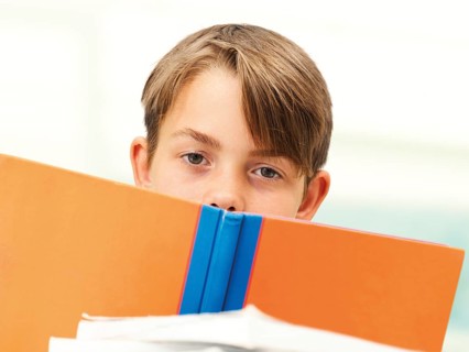 Schoolboy behind a school book