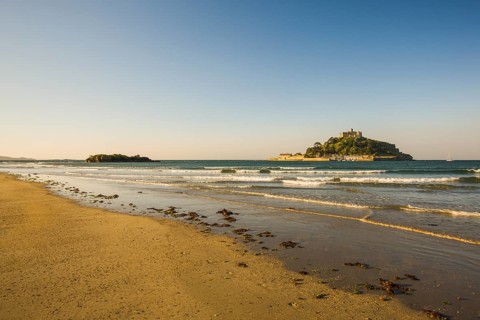 Sand beach with the island of St. Michael's Mount at high tide