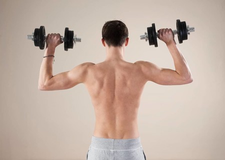 Young man doing weight training with dumbbells