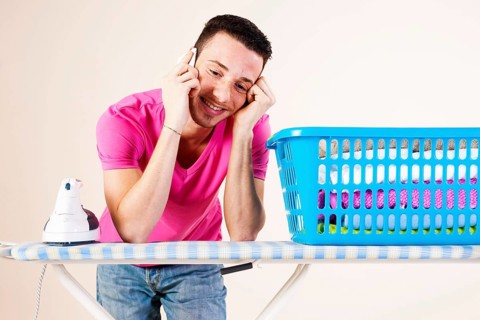 Young man talking on the telephone while leaning on an ironing board