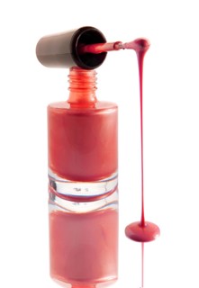 Nail varnish dripping from a nail varnish brush balanced on a nail varnish bottle