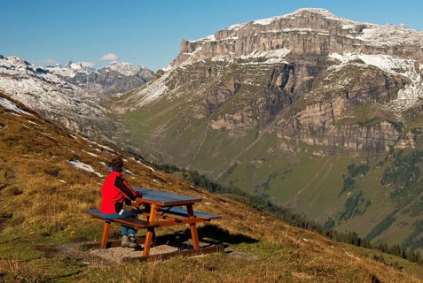 Walker looking from a rest area high above the Urnerboden high valley on the Klausen Pass
