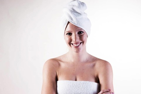 Portrait of a smiling young woman with a towel wrapped around her head