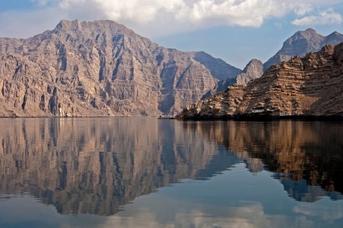 Reflection of a barren mountain range in the Khor Ash Sham Fjord