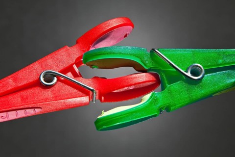 A red clothes-peg and a green clothes-peg are fighting with each other
