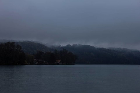 Autumn fog over the lake with a small church