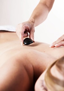 Young woman receiving a back massage with hot stones
