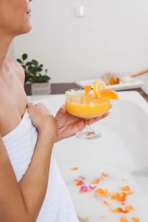 Woman drinking a cocktail in the bathtub