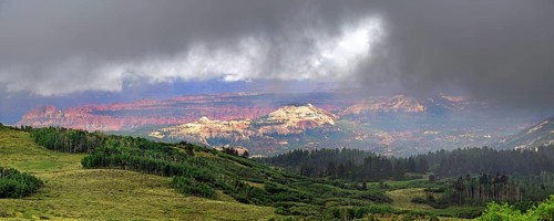 View through the clouds from the green forested Boulder Mountain towards Capitol Reef