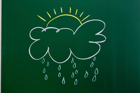 Cloud with a sun and rain drawn with chalk on a blackboard