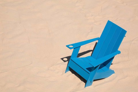 Blue adirondack chair standing on a beach