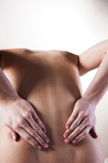 Bare back of a young woman with back pain