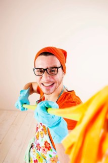 Young man wearing an apron and cleaning gloves holding a cleaning mop