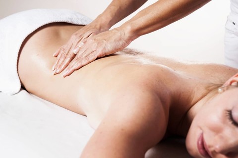 Young woman being massaged on the back by a therapist