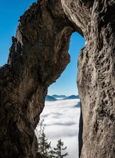 View through natural arch Breitensteinfensterl to high fog above the valley