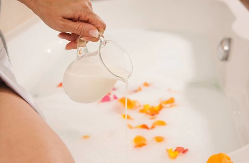 Woman pouring milk into a bath