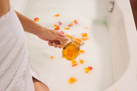Woman pouring bath oil in a bathtub