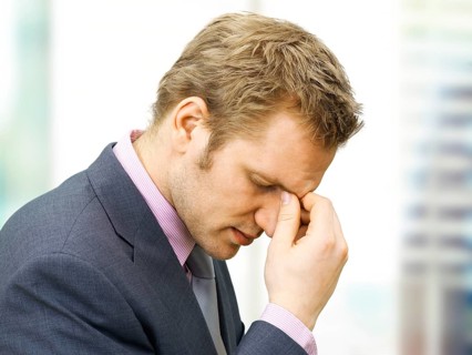 Stressed businessman holding a hand to the bridge of his nose
