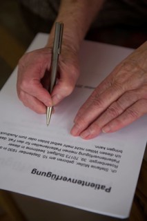 Hands of a 82-year-old woman signing a living will
