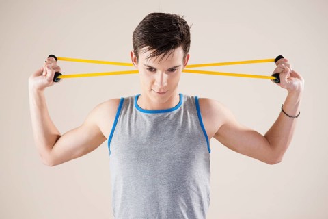 Young man doing fitness exercises with an expander