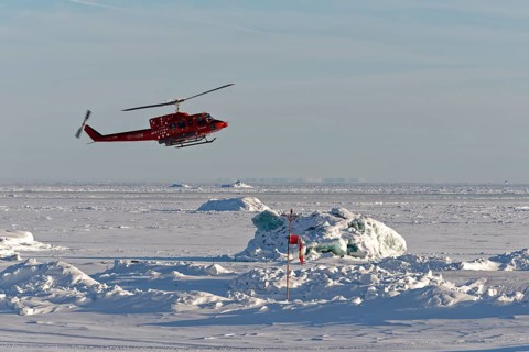 Helicopter lands on the helipad of Qeqertarsuaq