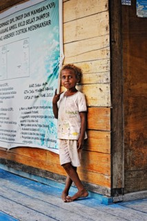 Local child standing against a wooden wall
