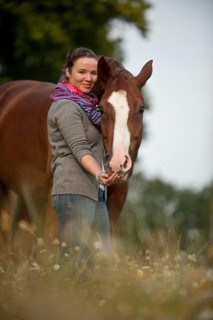 Woman standing next to a Hanoverian horse in a meadow