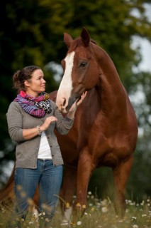 Woman standing next to a Hanoverian horse in a meadow