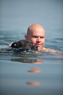 A man and a dog swimming in a lake
