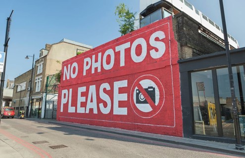 Graffiti 'No photos please' on a wall of the Village Underground building